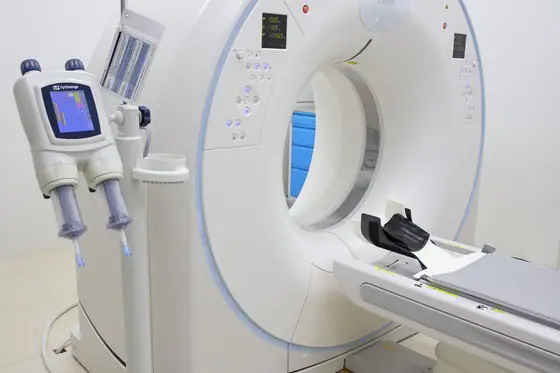 A computed tomography scanner and its patient table in a diagnostic imaging room