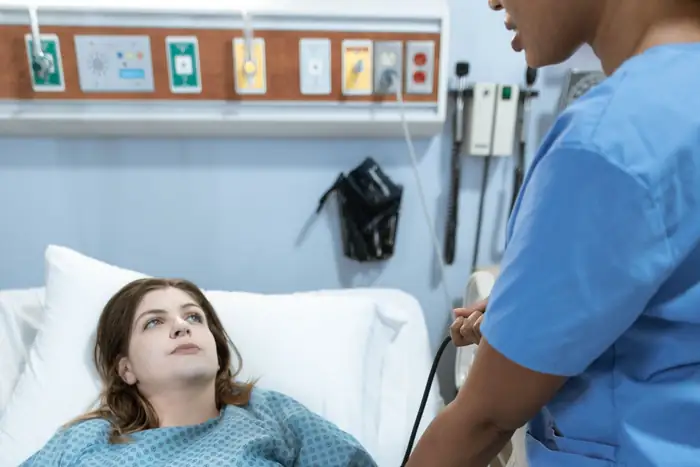 A nurse taking a patient’s blood pressure at the bedside on a hospital ward