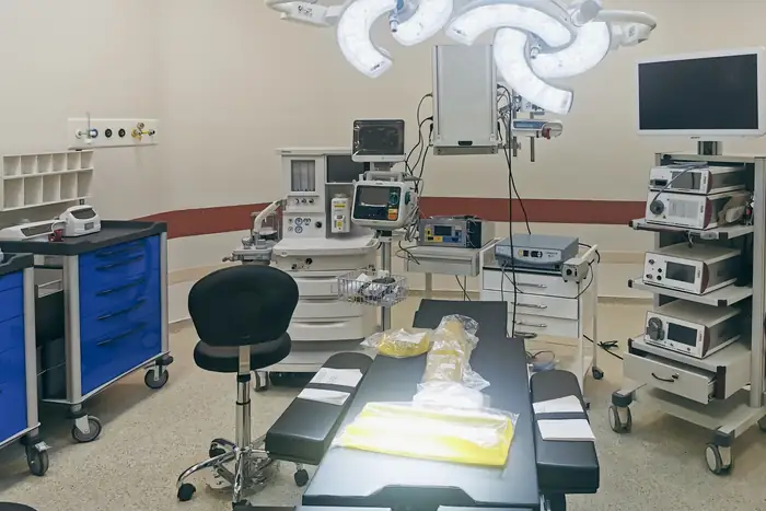 A fully equipped operating room with anaesthetic and monitoring trolleys around the table