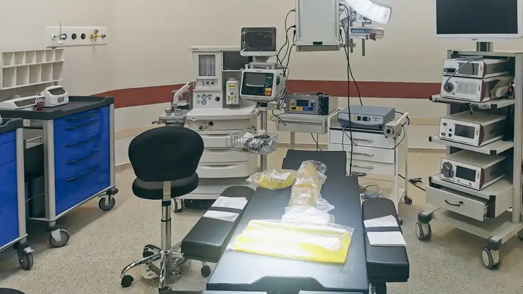 A fully equipped operating room with anaesthetic and monitoring trolleys around the table